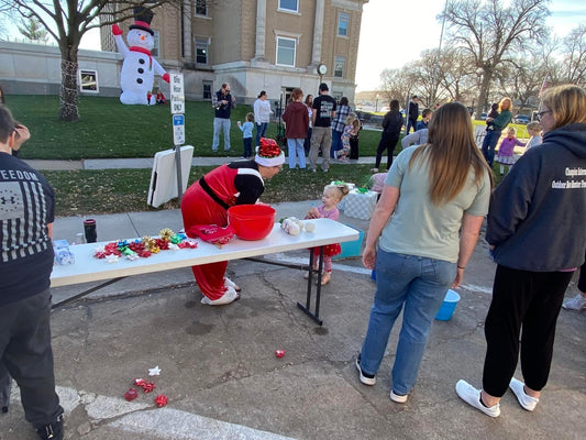 picture of a bow activity in front of the courthouse.  multiple people are gathered around a table with bows on it.